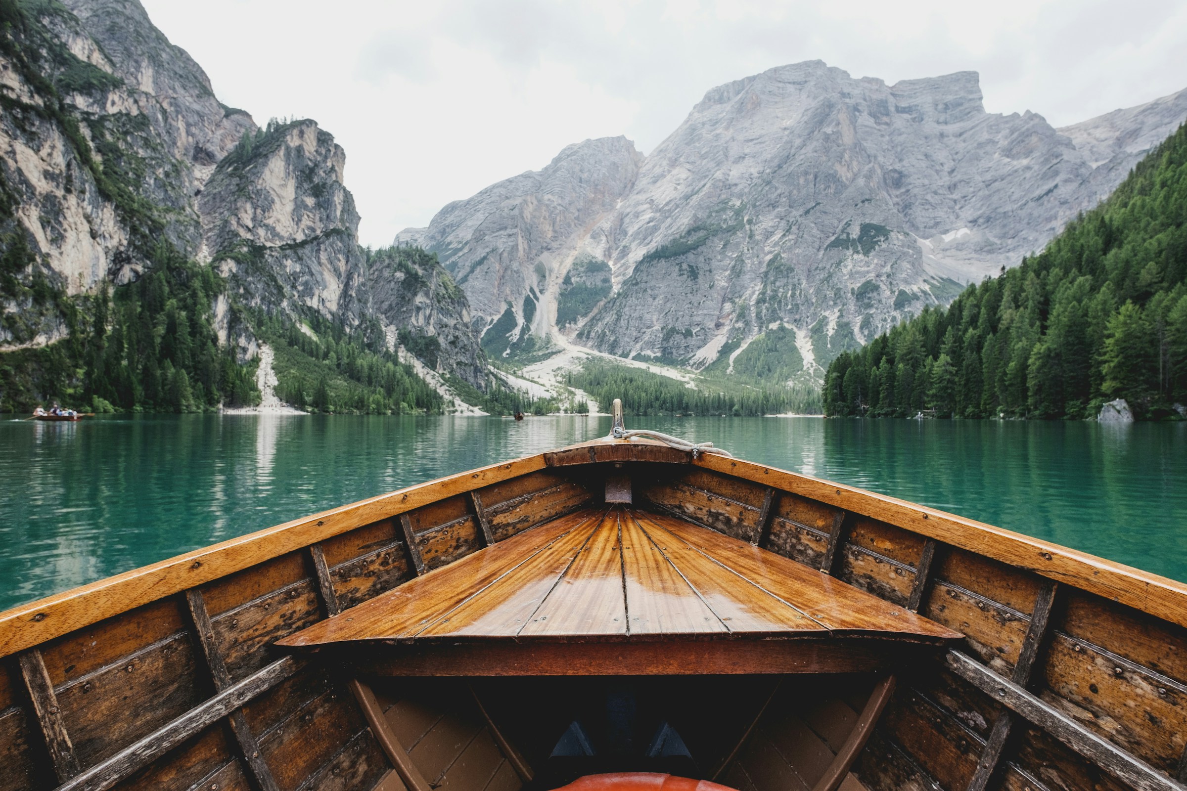 Bow of a wooden boat gliding on the emerald Lago di Braies